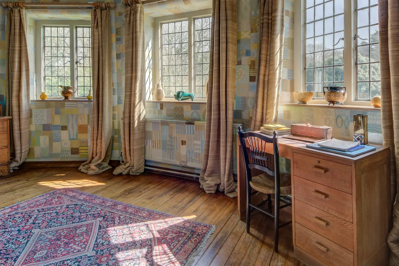 Home study with a solid wood desk, leaded windows and a vintage rug
