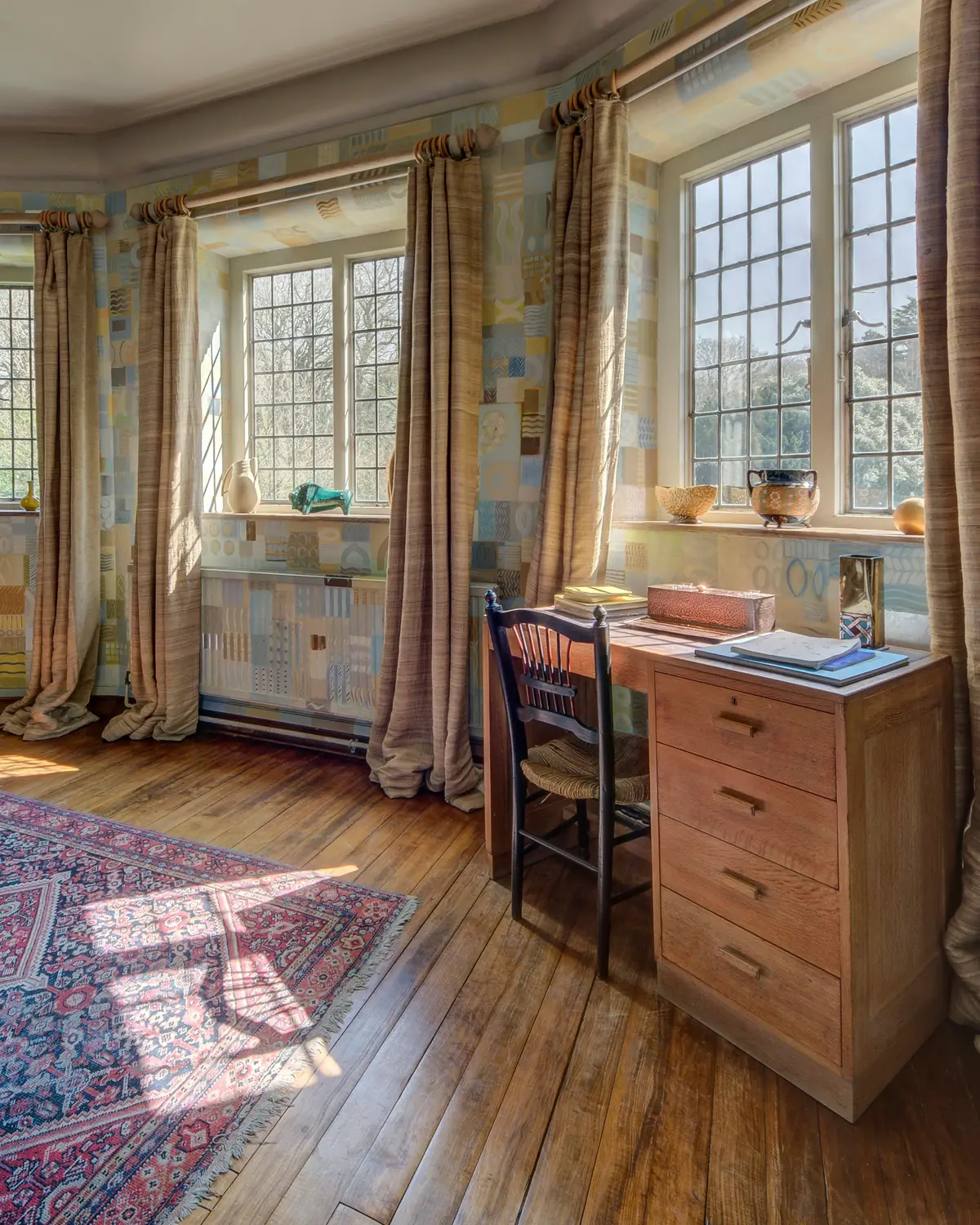 Home study with a solid wood desk, leaded windows and a vintage rug