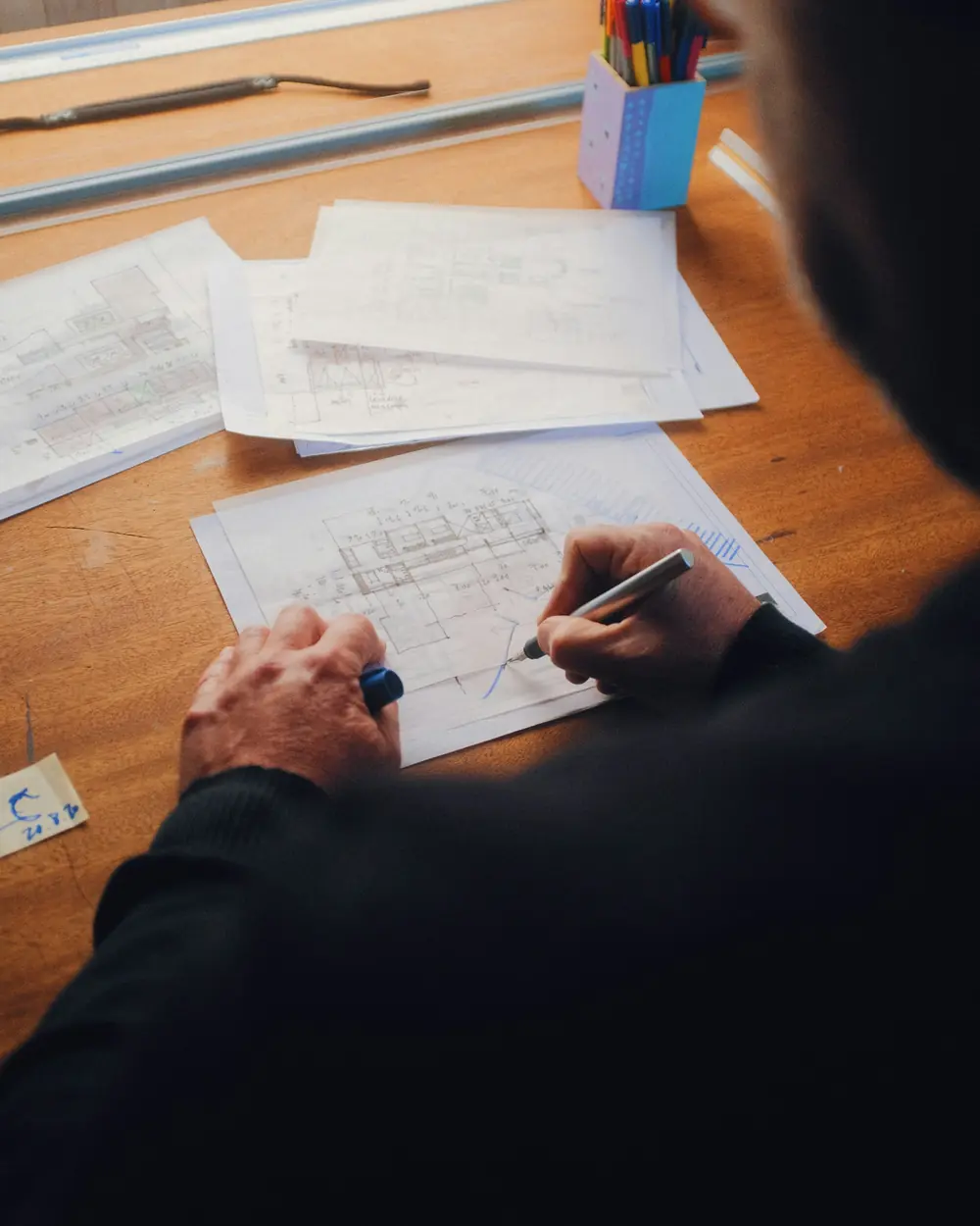 Designer sketching on paper at a wooden desk during a consultation