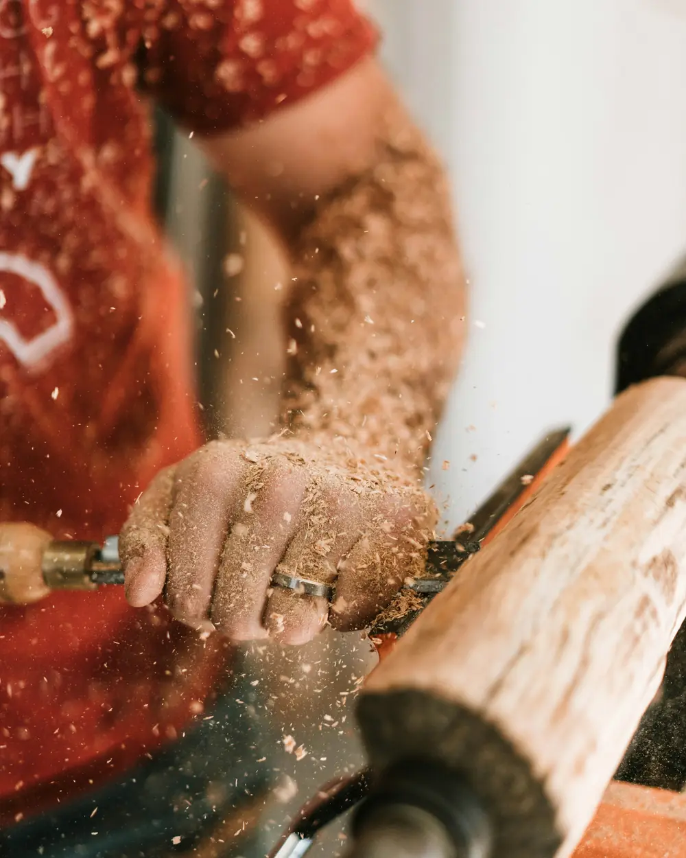 Craftsman turning solid wood on a lathe with shavings flying