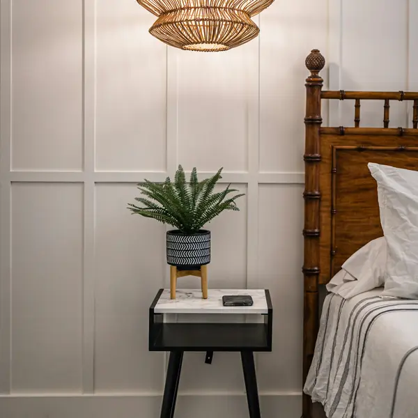 Rattan pendant above a bedside table and cane bed