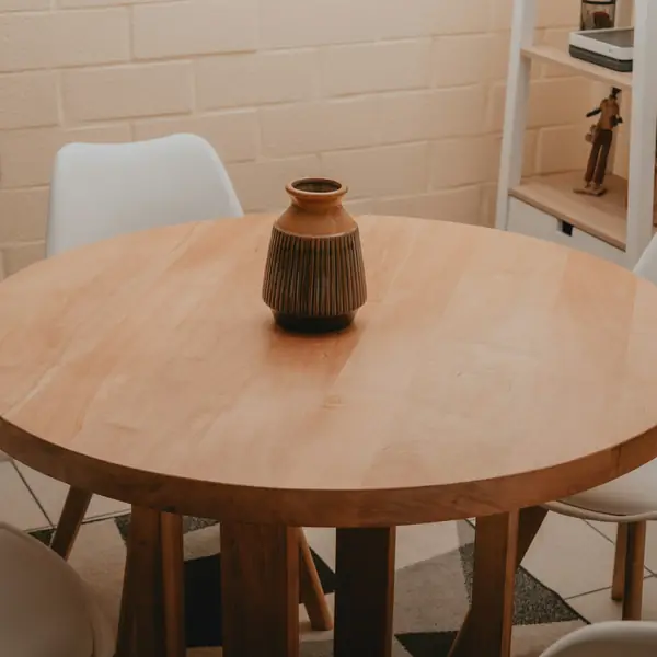 Round wooden dining table with a ceramic vase