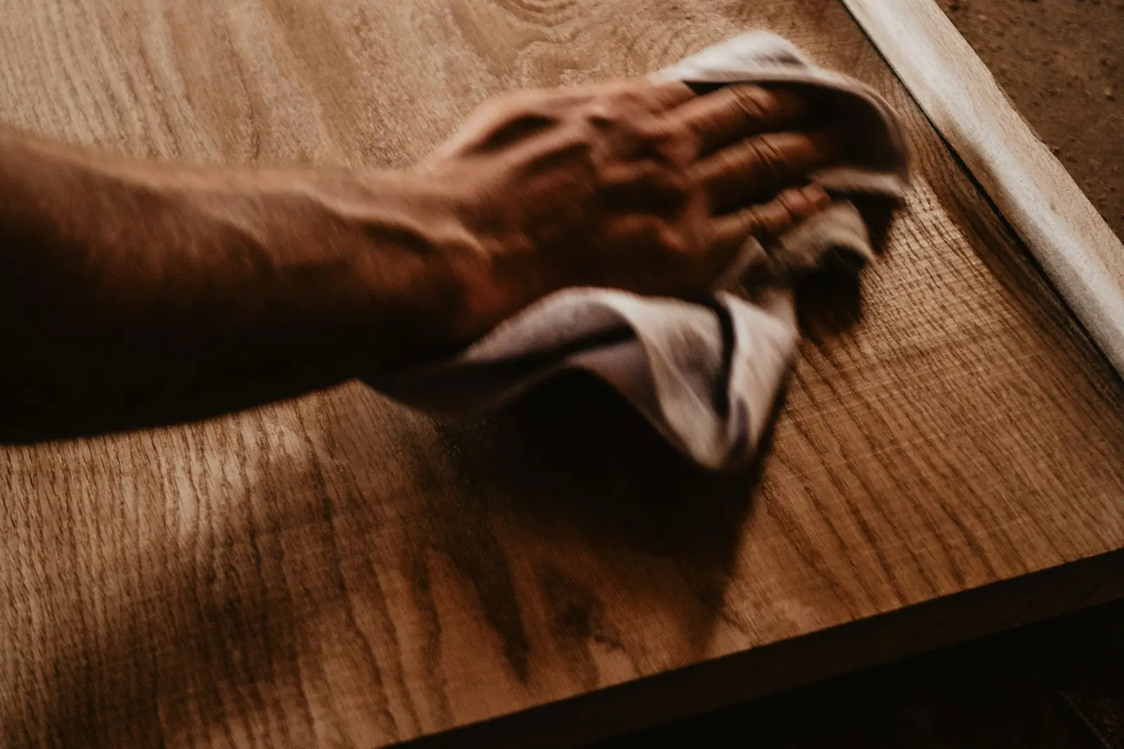 Close-up of a hand polishing wood grain with a cloth