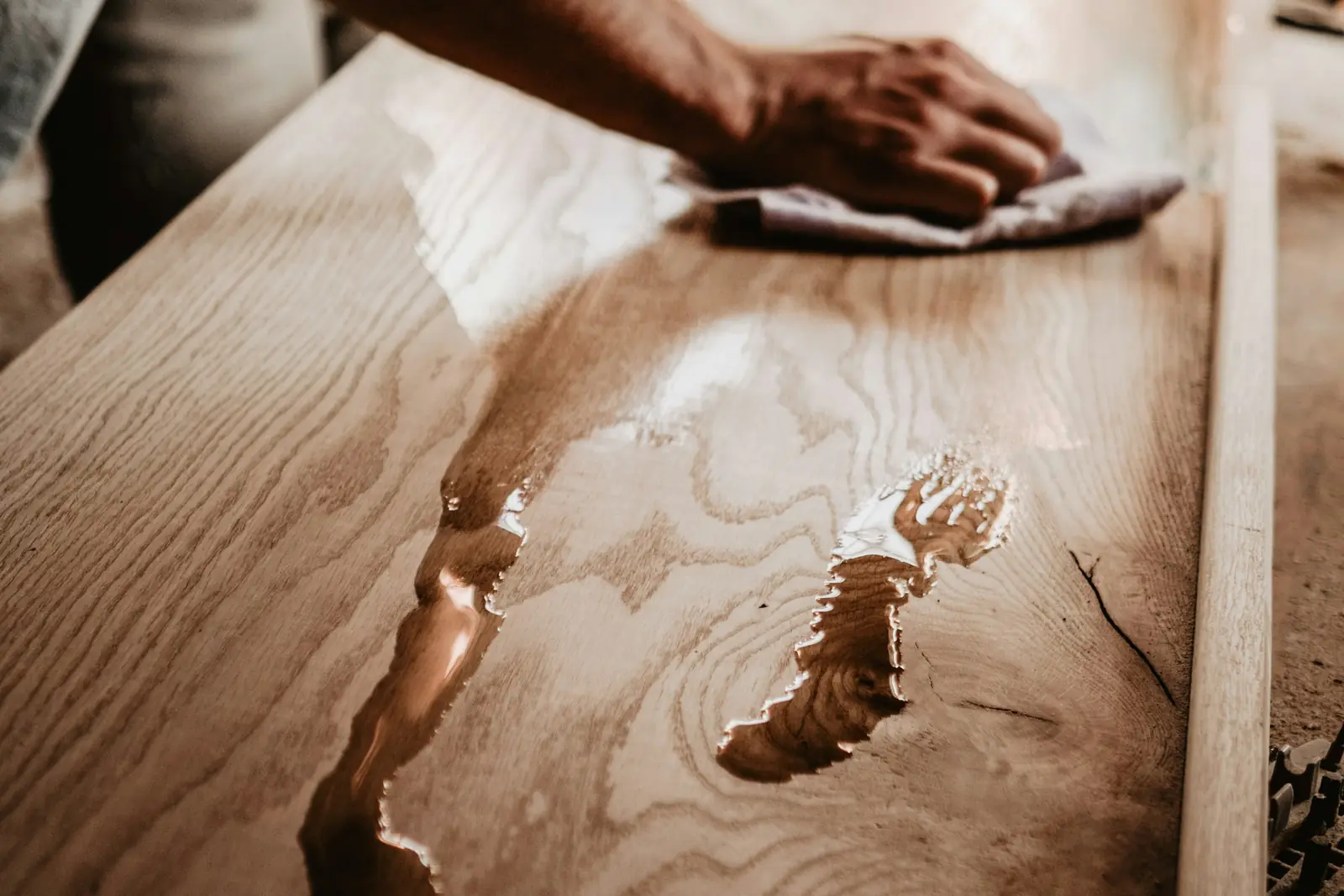 Hand wiping a solid wood table with a soft cloth
