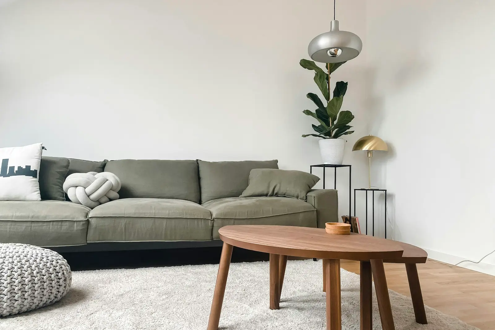 Sage sofa and an oval wooden coffee table in a calm, minimal room