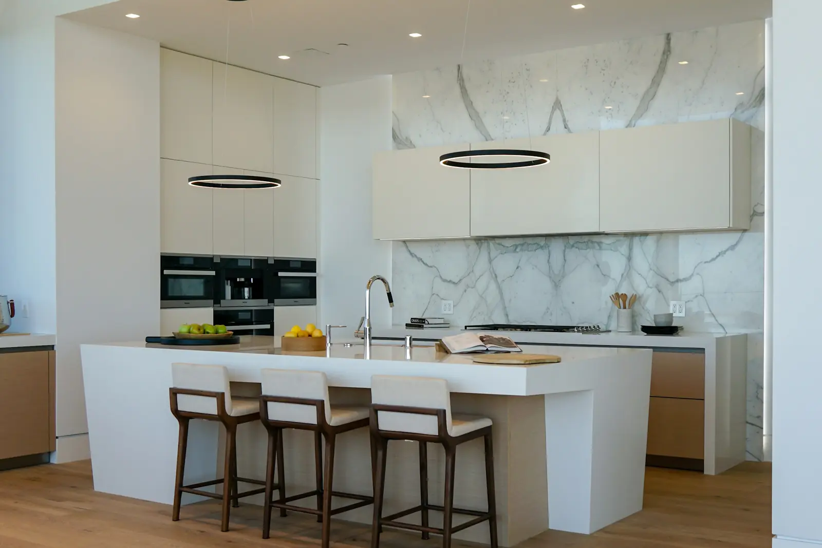 White modular kitchen with an island, breakfast bar and ring pendant