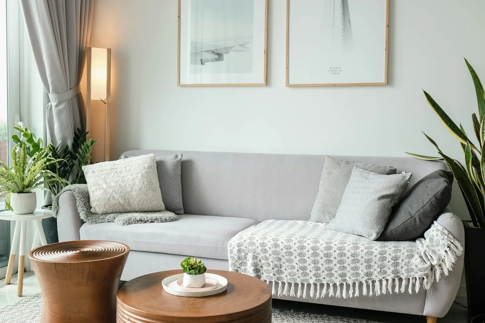 Small bright living room with a pale sofa, round coffee tables and a knitted pouf