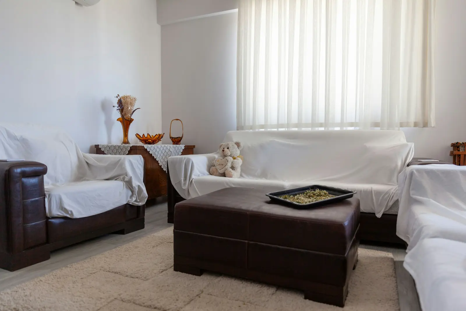 Living room with draped sofas around a dark leather ottoman