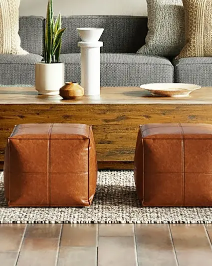 Pair of tan full-grain leather poufs on a woven rug