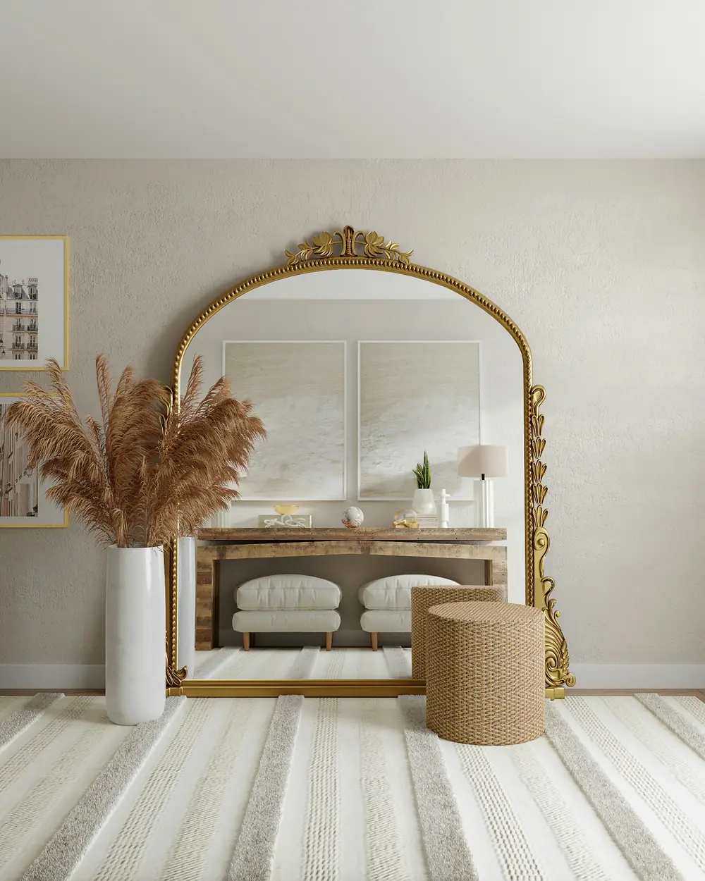 Tall gilded arched mirror above a console with pampas grass and a woven pouf