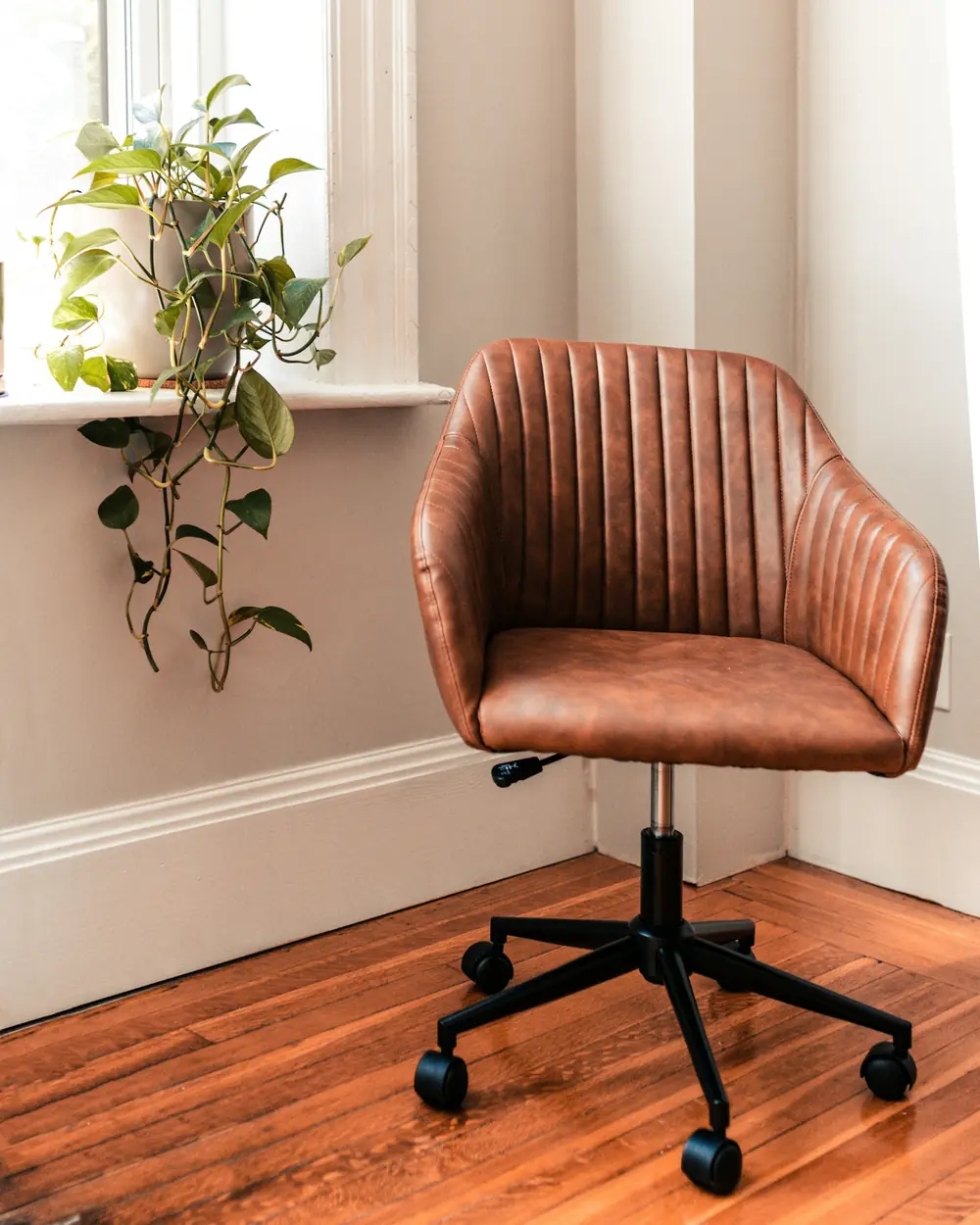 Channel-stitched tan leather executive chair beside a sunny window