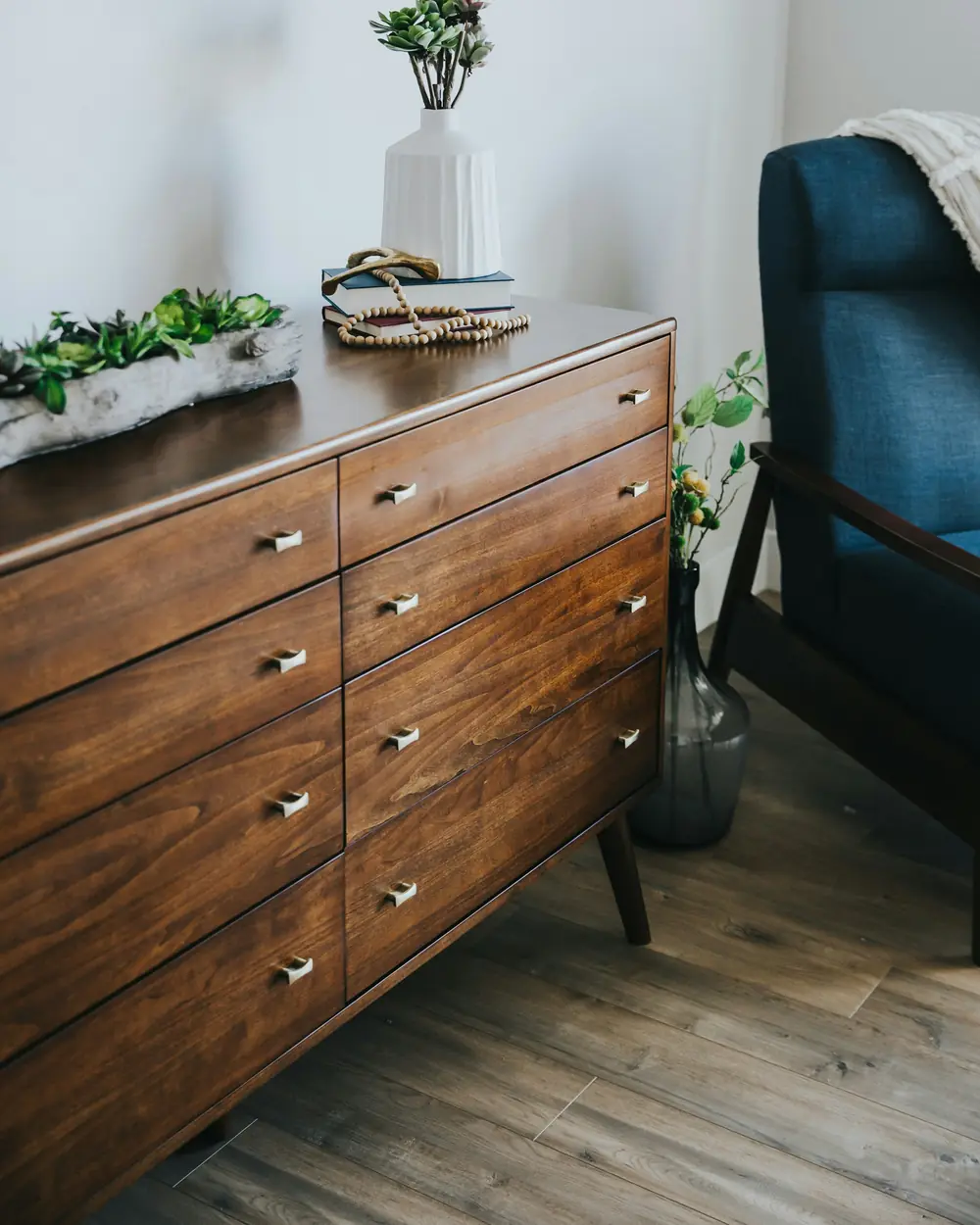 Walnut-finish chest of drawers on tapered legs with slim brass pulls