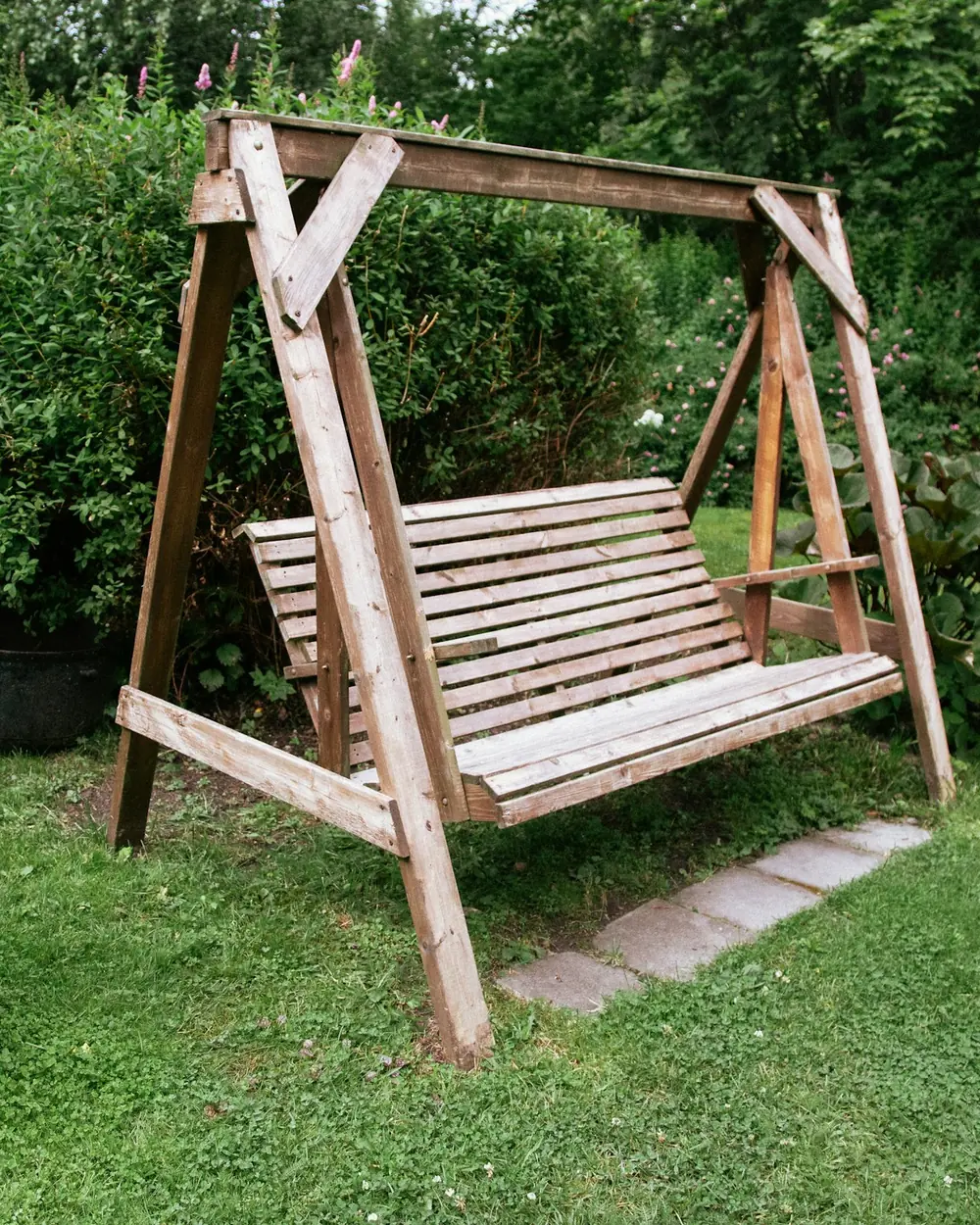 Solid wood garden swing on an A-frame stand in a green lawn