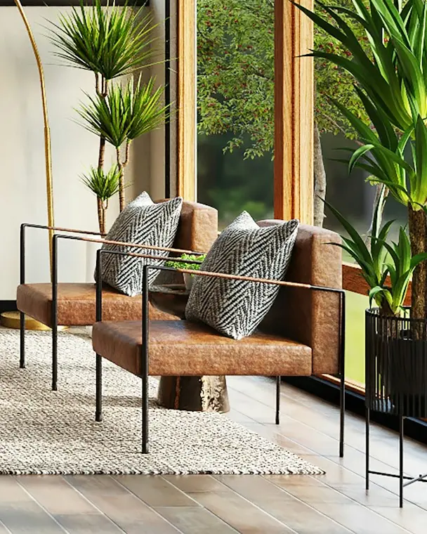 Tan leather sling armchairs on blackened steel frames with patterned cushions