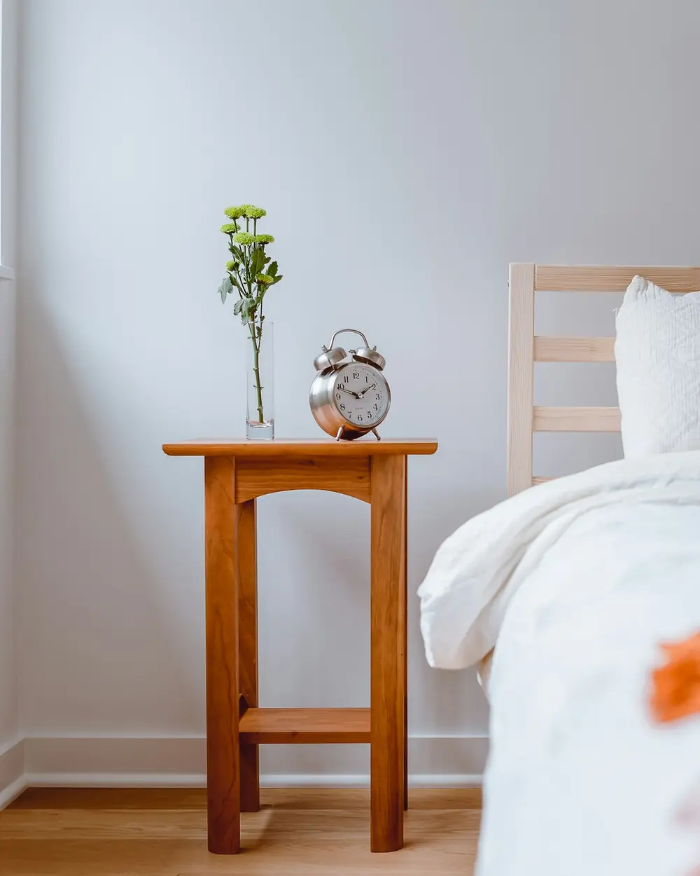 Solid teak bedside table with a lower shelf beside a white bed