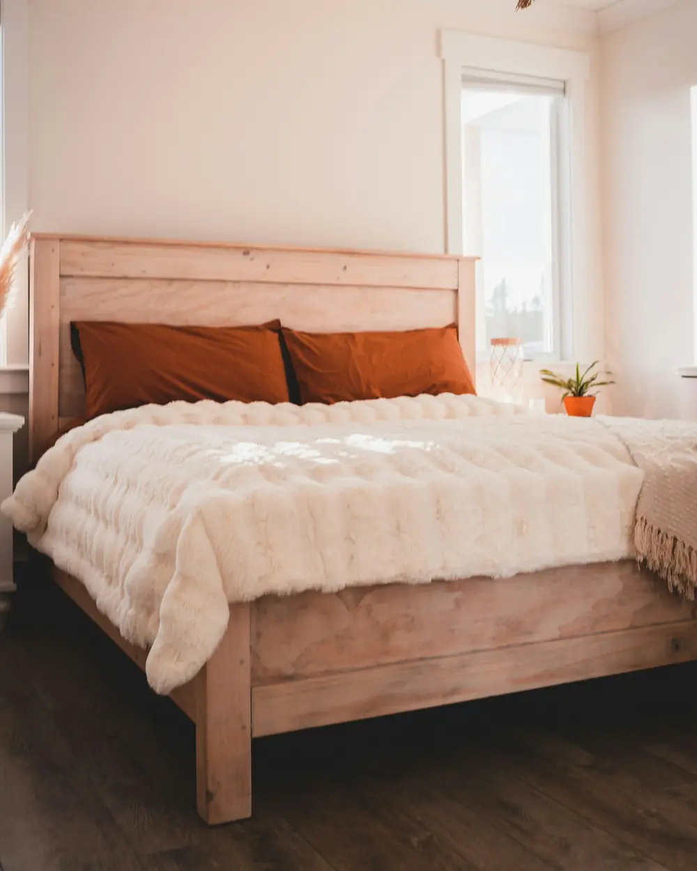 Solid wood king bed with a plank headboard, ivory throw and rust linen pillows
