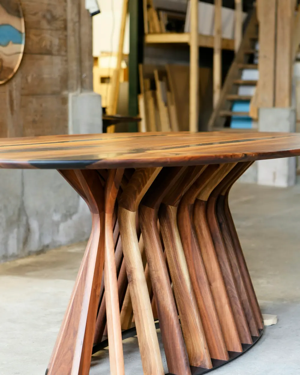 Sculptural dining table with a pedestal of fanned solid teak staves