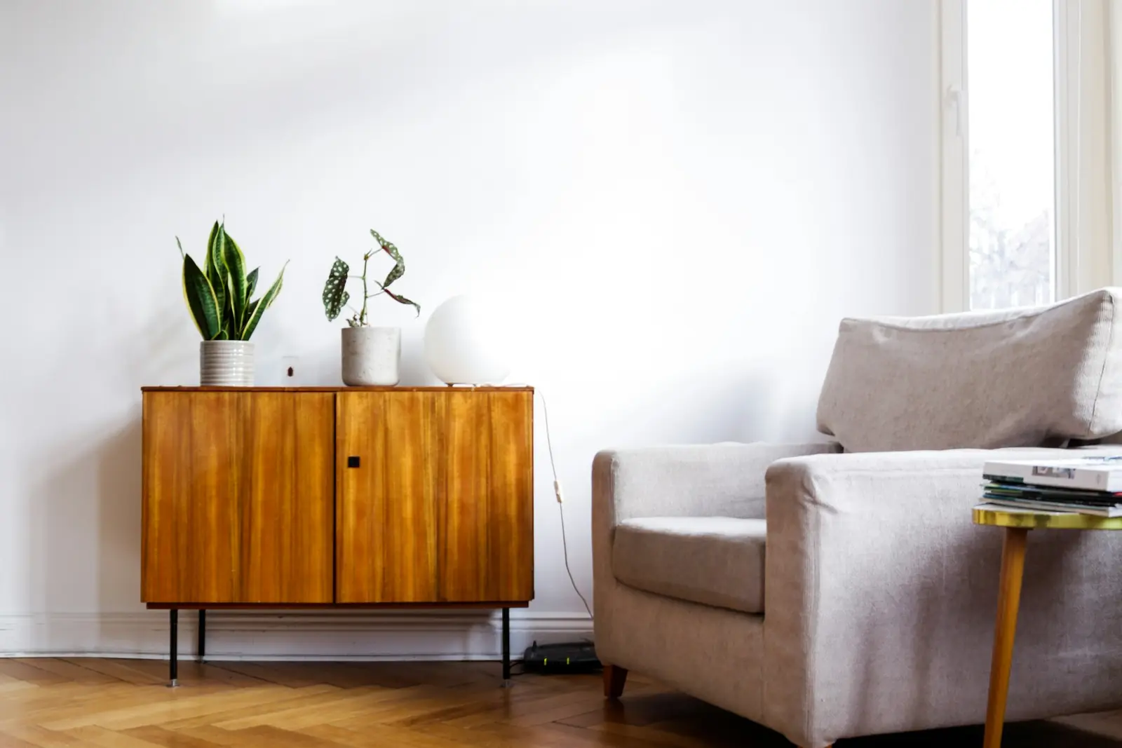 Minimal living corner with a mid-century sideboard and an upholstered armchair
