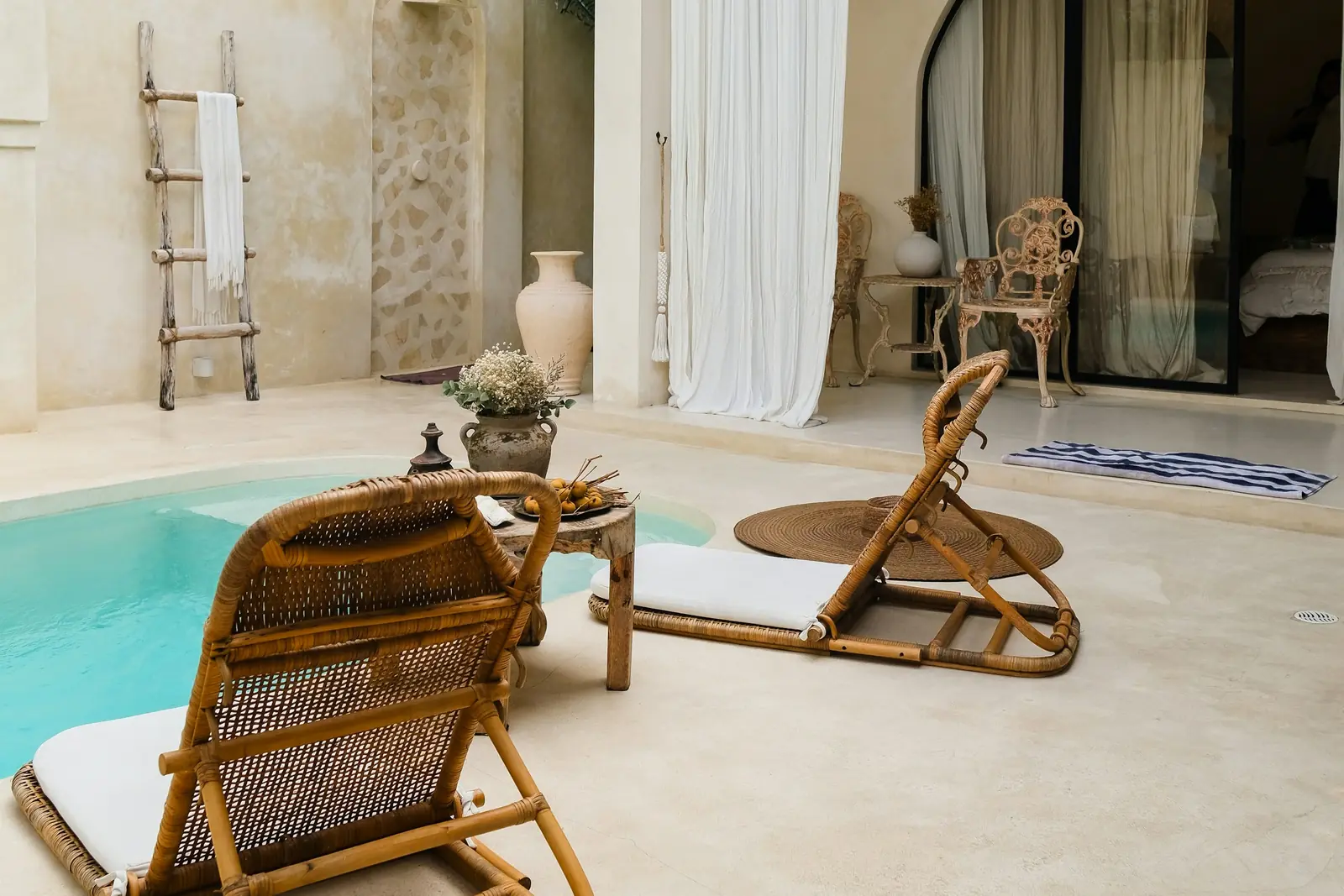 Villa courtyard with a plunge pool, cane loungers and arched openings