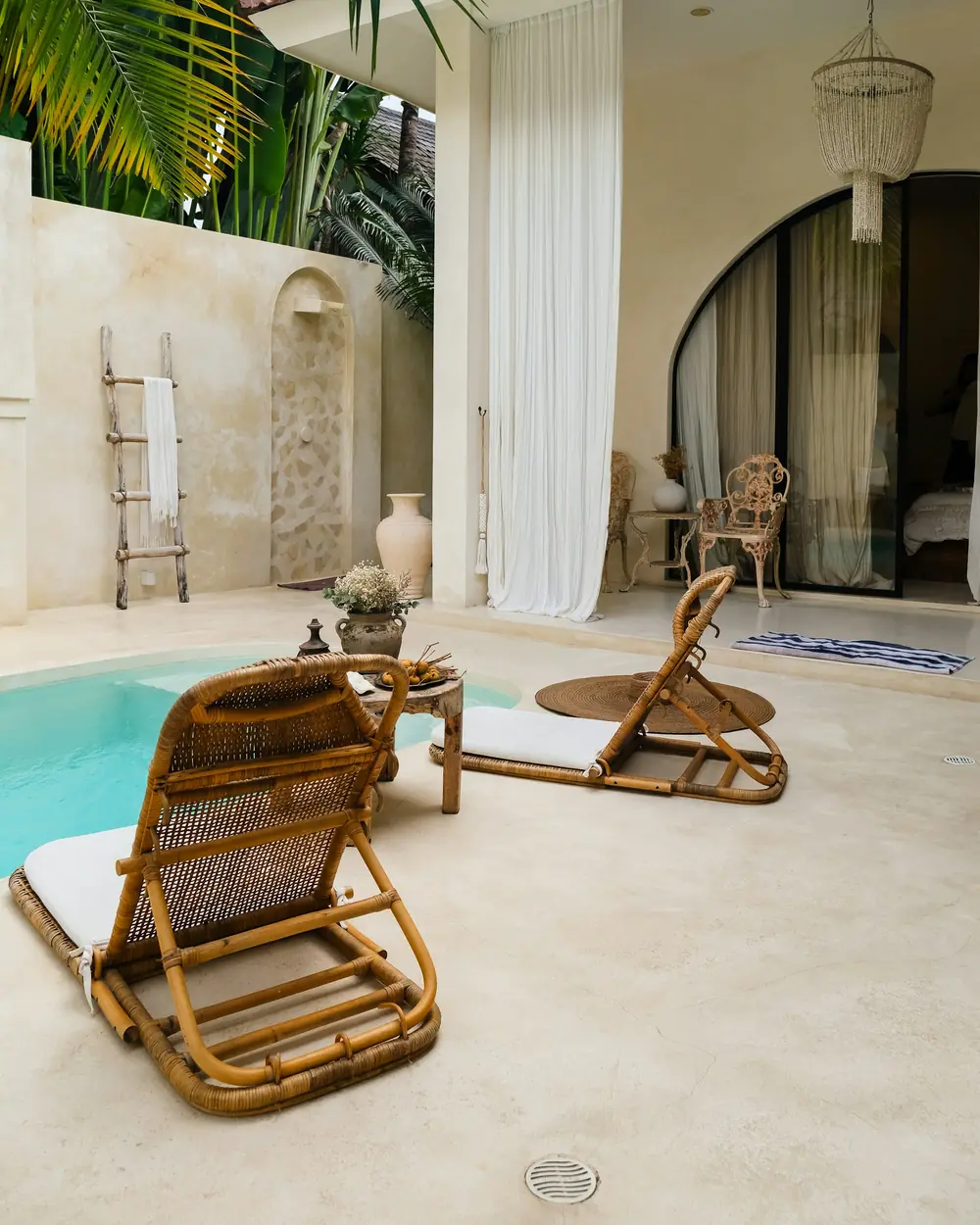 Villa courtyard with a plunge pool, cane loungers and arched openings
