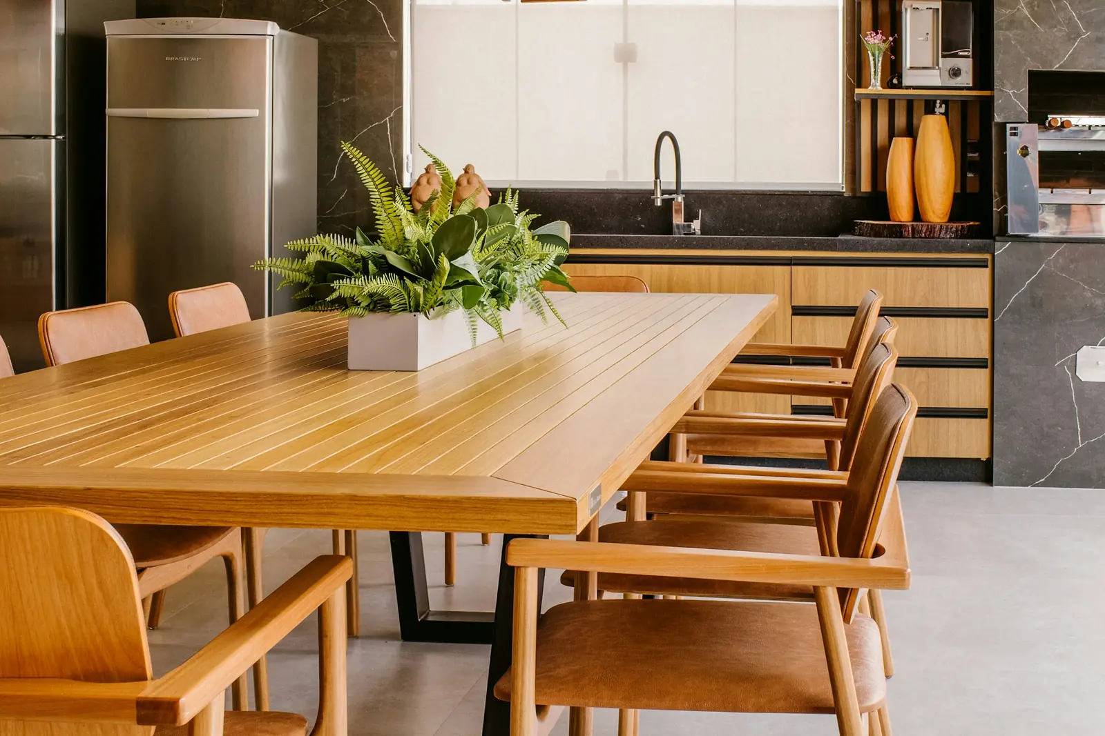 Open kitchen with wooden cabinets and a long oak dining table