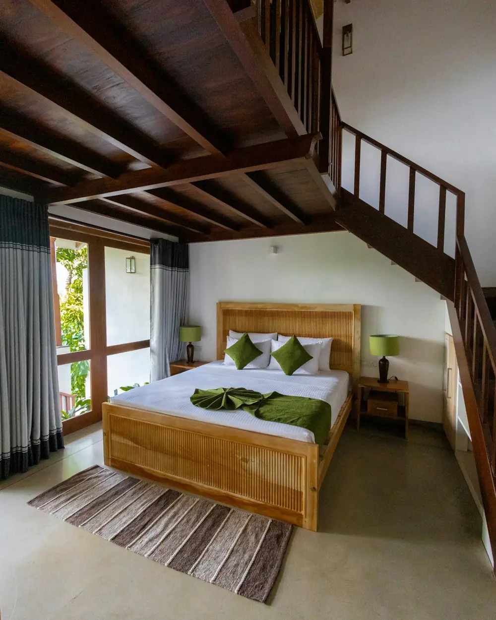 Bedroom under a timber ceiling with a solid wood bed and a wooden staircase