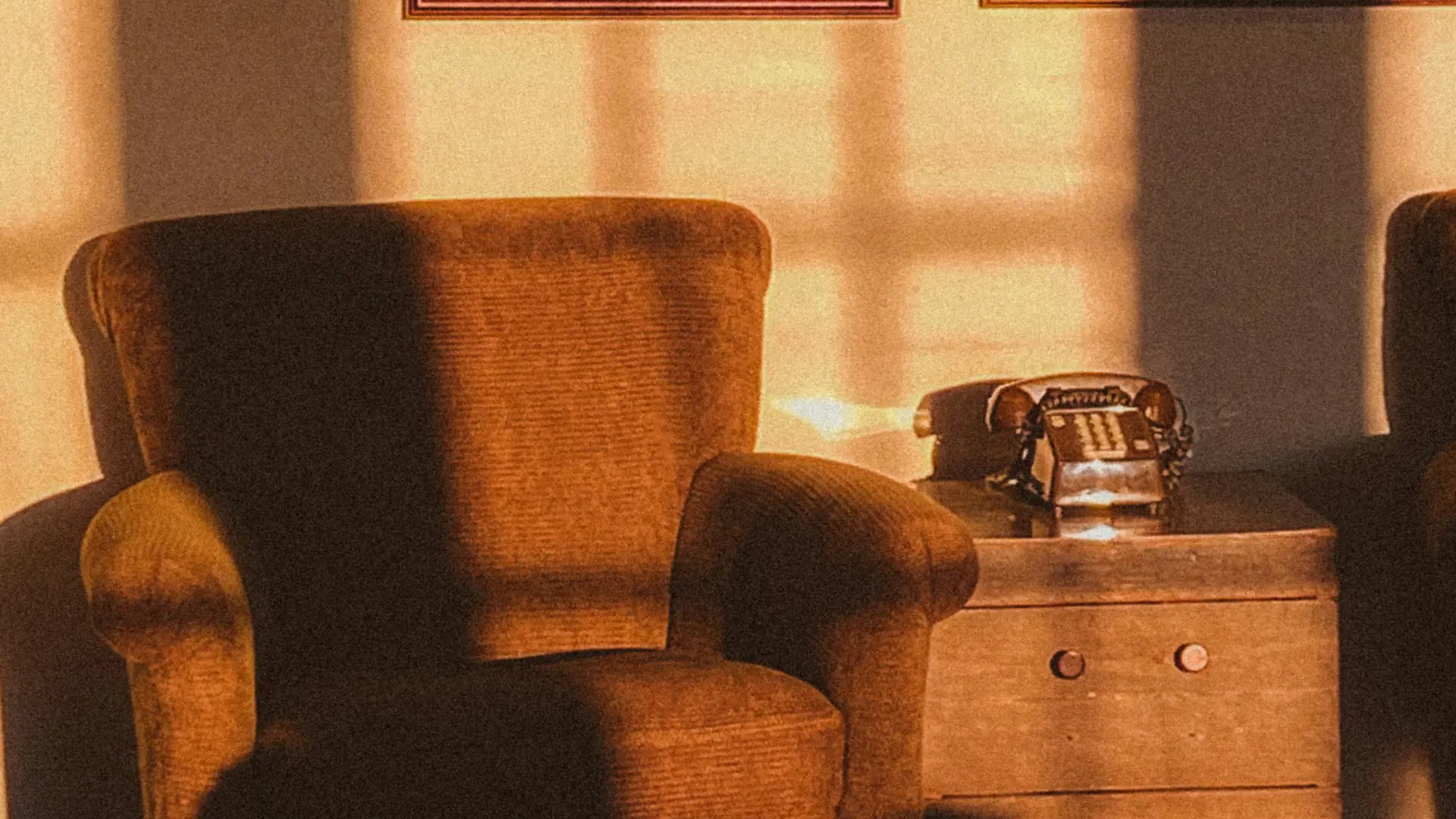 Velvet armchair and wooden chest bathed in warm late-afternoon light