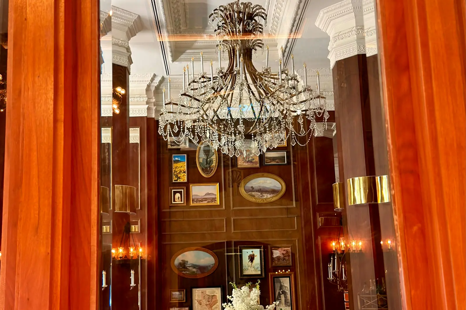 Art Deco dining room with a crystal chandelier, wood panelling and burnt-orange drapes